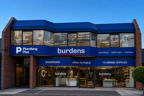 The exterior of the 'burdens Plumbing Plus' showroom in Mictham, featuring a modern brick facade, a prominent blue metal roof, and large glass windows displaying plumbing fixtures inside.